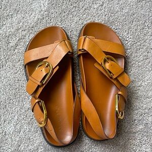 Tan leather and chunky metal hardware buckle sandals.